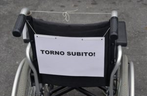 carrozzina con cartello ironico "torno subito"