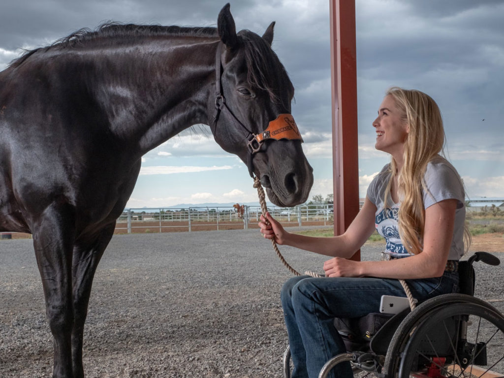 una ragazza in sedia a rotelle con un cavallo